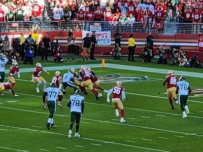 NFL game action with players on the field and fans in the stands