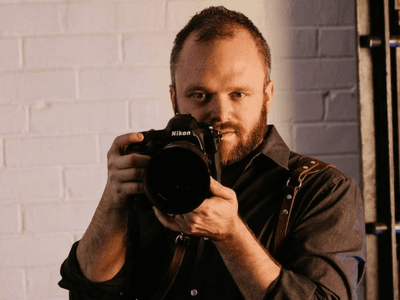 A photographer holding a Nikon camera, focused and ready to capture a shot