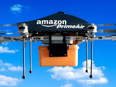Amazon Prime Air drone flying against a blue sky carrying an orange package