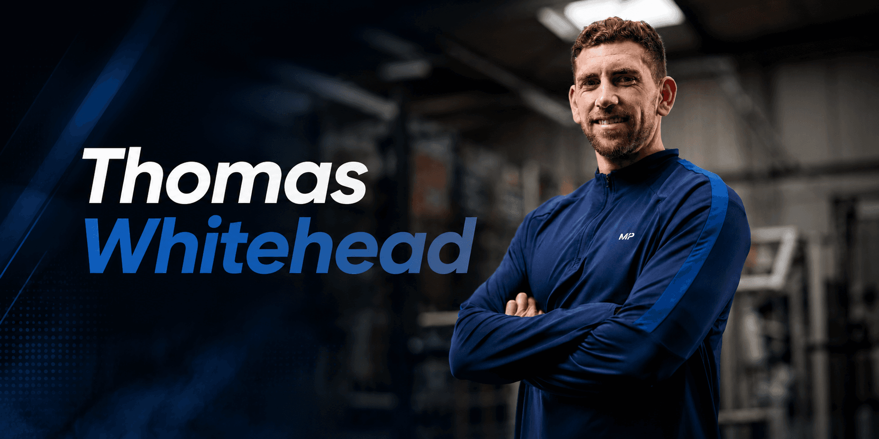A man in a blue jacket smiling confidently in a gym setting