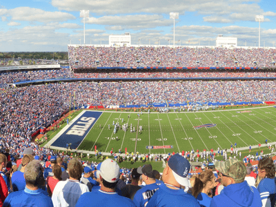 Panoramic view of a packed football stadium with fans cheering during a game