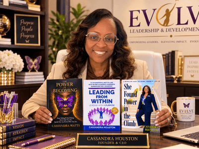A woman sits at a desk with her books, promoting her leadership development business.