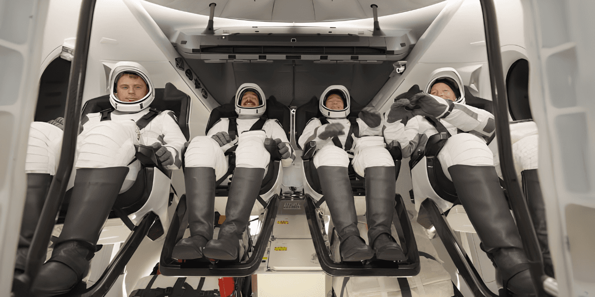 Four astronauts seated inside a spacecraft, wearing space suits and helmets, prepared for launch